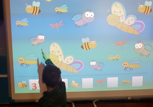 chłopiec wykonuje „wiosenne zadanie” na tablicy multimedialnej